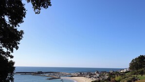 Un pueblo costero con playa arenosa, un puerto deportivo y edificios residenciales.
