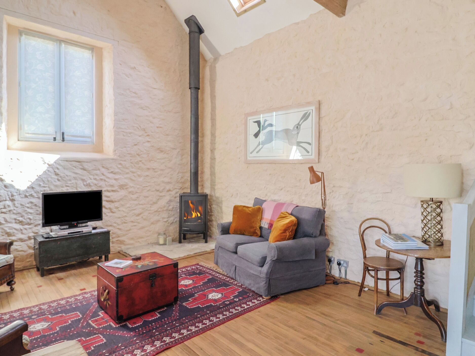 Una sala de estar acogedora con chimenea, un sofá, un televisor y una alfombra.