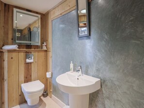 A bathroom with a wooden vanity, a white sink, and a toilet.