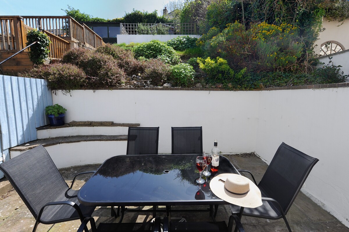 A patio with a table and chairs, a hat, and a bottle of wine.
