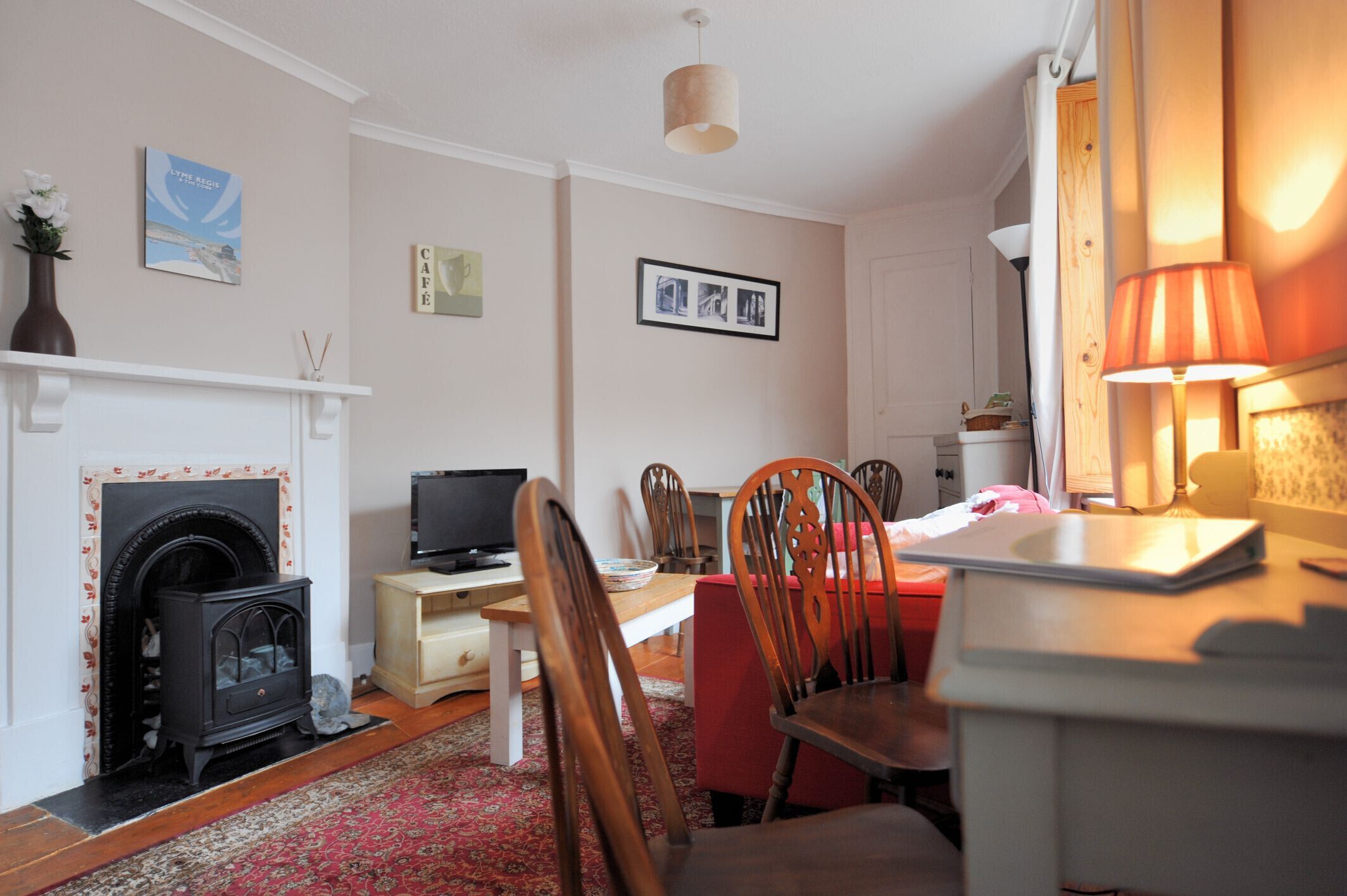 A cozy living room with a fireplace, a television, a dining table with chairs, and a lamp.