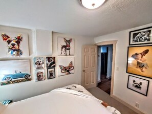 Ein Schlafzimmer mit einem Bett, einer Tür und Wänden, die mit Hunde-Kunstwerken verziert sind.