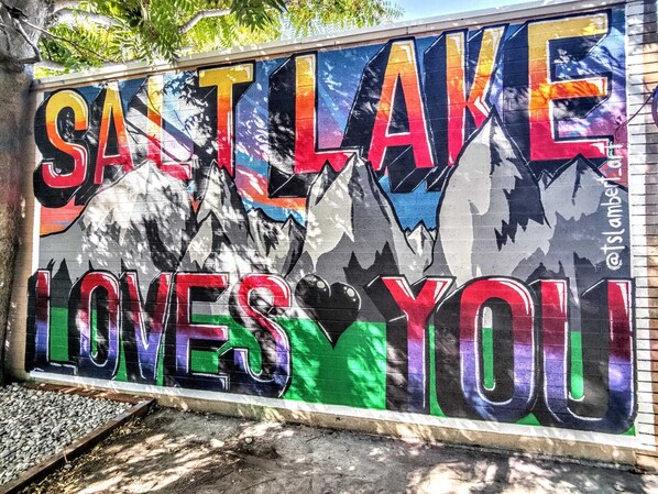 Ein farbenfrohes Wandbild mit dem Schriftzug "SALT LAKE LOVES YOU" und Bergkonturen.
