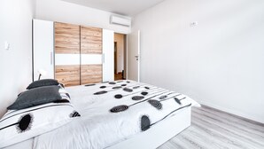 Quarto moderno com cama, guarda-roupa de madeira e ar condicionado.