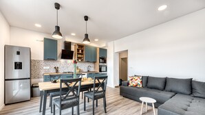 Cozinha moderna com área de refeições, um sofá cinza e uma mesa pequena.