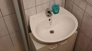 Un baño con un lavabo blanco, un grifo y un dispensador de jabón.
