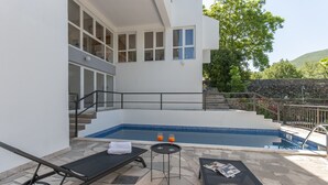 A modern outdoor pool area with a stone floor, lounge chairs, and a small table with drinks. - Villa Green Castle - Five bedroom villa with swimming pool (Zadvarje)