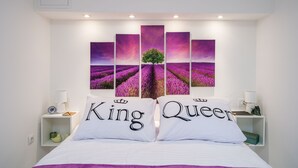 A bedroom with a bed, two nightstands, a wall-mounted artwork of lavender fields, and pillows labeled "King" and "Queen". - Apartment Laneta - Studio Apartment with Terrace (Dubrovnik)