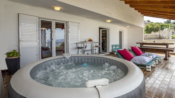 Een hottub met een houten plafond en een terras met zitplaatsen en een tafel.