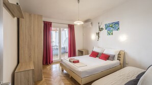 Een slaapkamer met een bed, een houten garderobe, een schuifdeur van glas en een plafondlamp.