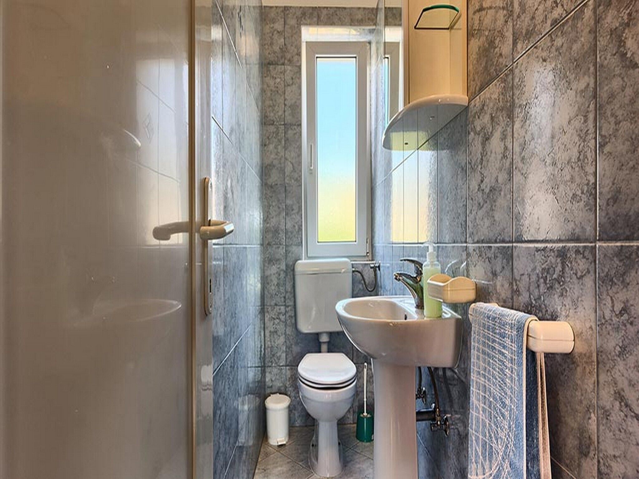 A bathroom with a toilet, sink, and a window.