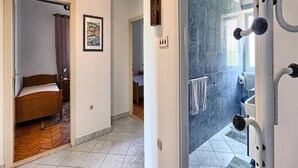 Una habitación de hotel con cama, zona de ducha con puerta de cristal y baño con toallero.