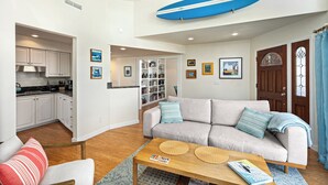 Un salon avec un canapé, une table basse et une planche de surf accrochée au plafond.