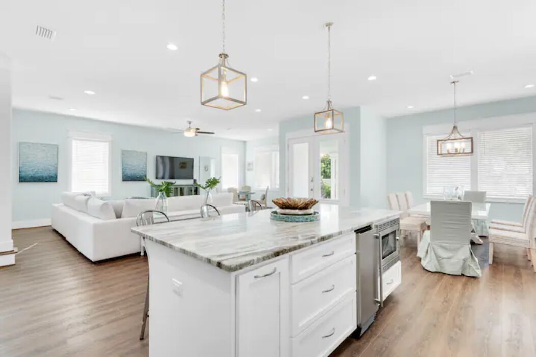 A spacious kitchen with a central island, white cabinetry, and pendant lighting.