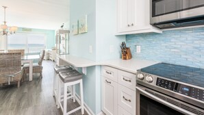 Una cocina con armarios blancos, un microondas de acero inoxidable y un salpicadero de azulejos azules.