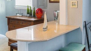 Una cocina con una isla central, taburetes de bar, iluminación colgante y una ventana con cortinas de estampado de estrellas.