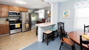 Una cocina moderna con armarios de madera, electrodomésticos de acero inoxidable y una isla central con taburetes de bar.