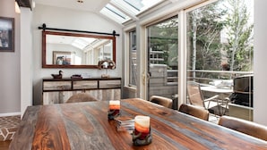 A dining area with a wooden table, two candles, and a view of the outdoors through large windows. - Villas of Aspen by Snowmass Vacations (Aspen)