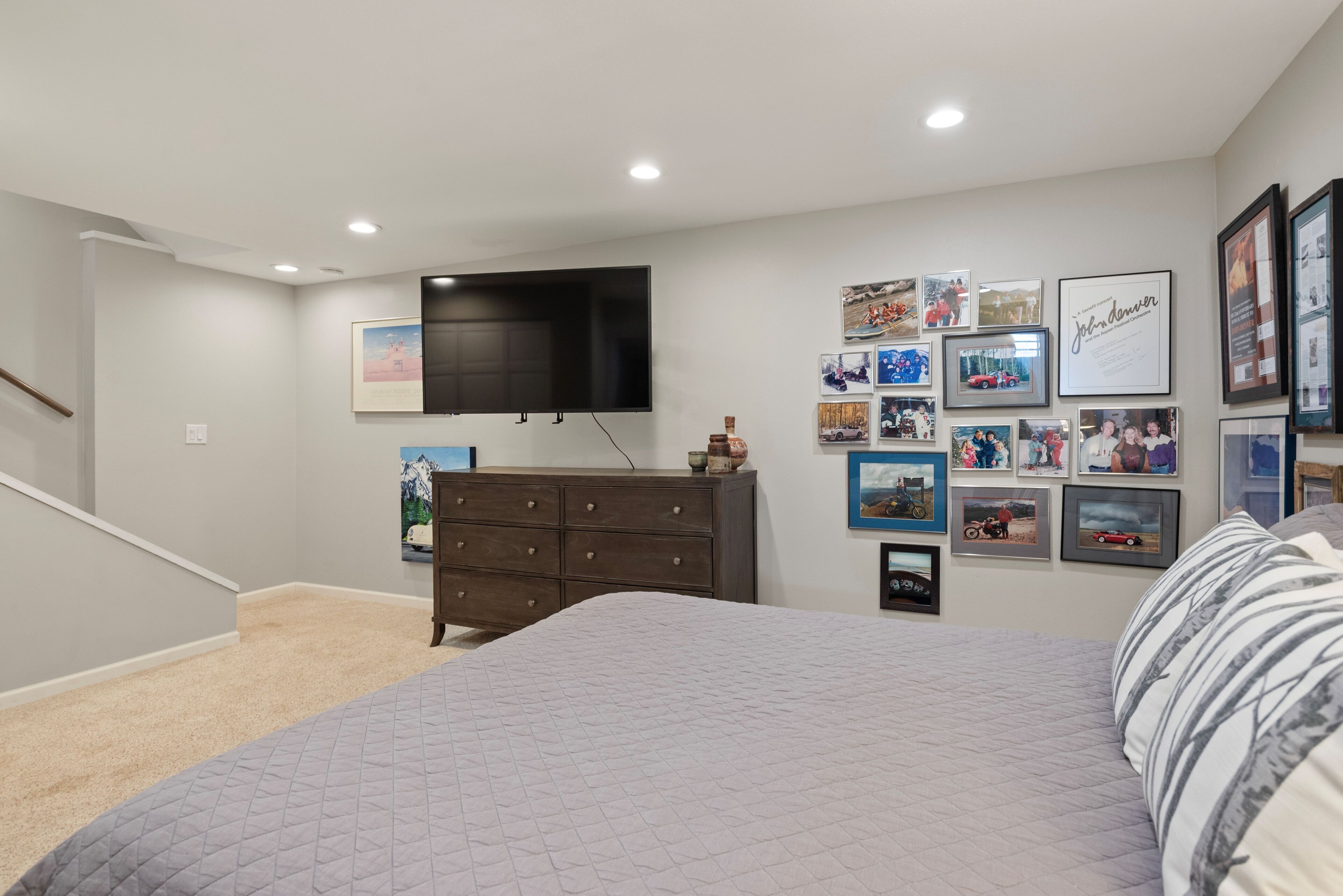 Camera da letto con un letto, una cassettiera e una TV a parete.