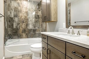A modern bathroom with a bathtub, toilet, and vanity with a mirror. - Villas of Aspen by Snowmass Vacations (Aspen)