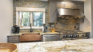 A kitchen with granite countertops, a built-in stove, and stone backsplash. - Villas of Aspen by Snowmass Vacations (Aspen)