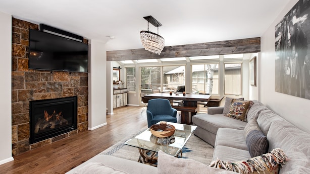 A spacious living room with a fireplace, a dining area, and a kitchen in the background. - Villas of Aspen by Snowmass Vacations (Aspen)