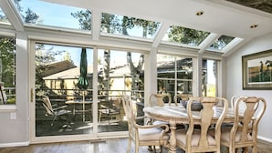 A conservatory with a dining table and chairs, large glass doors, and a view of the outdoors. - Villas of Aspen by Snowmass Vacations (Aspen)