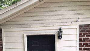 A black door with a small porch light above it, a metal bench, and a potted plant on the porch. - Glamping with a twist (Jacksonville)