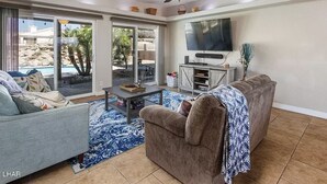 A living room with a sofa, a coffee table, a TV, and a ceiling fan.