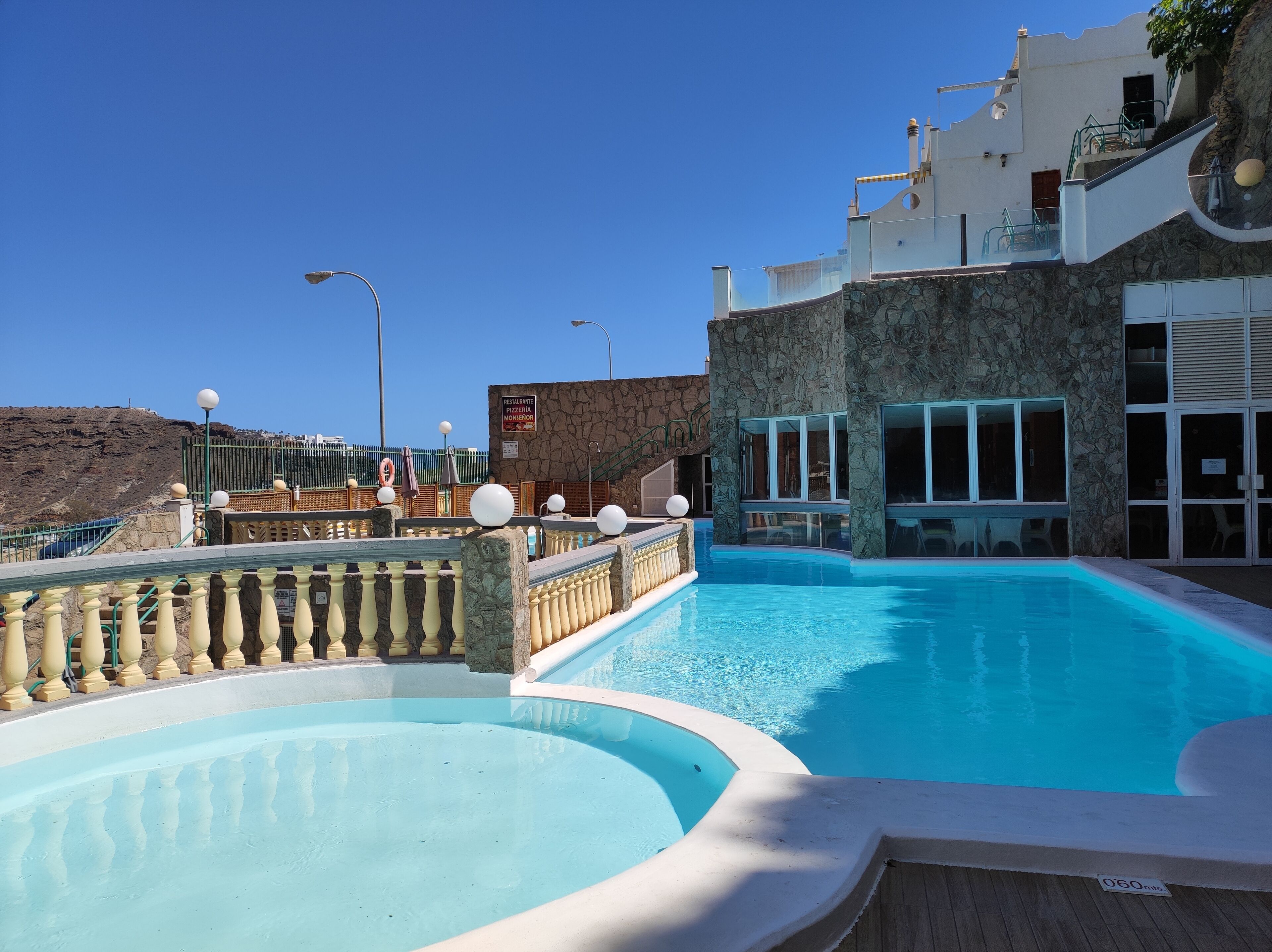 Une piscine avec une façade en pierre et une enseigne de restaurant.