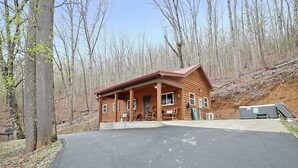 A wooden cabin with a porch, a covered outdoor seating area, and a large RV parked nearby. - Couples Retreat Cabin w HotTub & EV Charger Bryson (Bryson City)