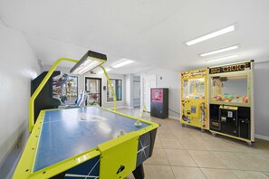 Une pièce équipée d’un baby-foot, de machines à pinces et d’une porte donnant sur un autre espace.