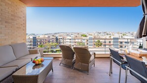 Un balcon agrémenté de meubles en osier, une table avec des fruits et une vue sur la ville.