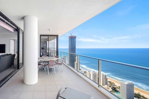 Enjoy the ocean view and city skyline from this balcony with a round table and chairs.