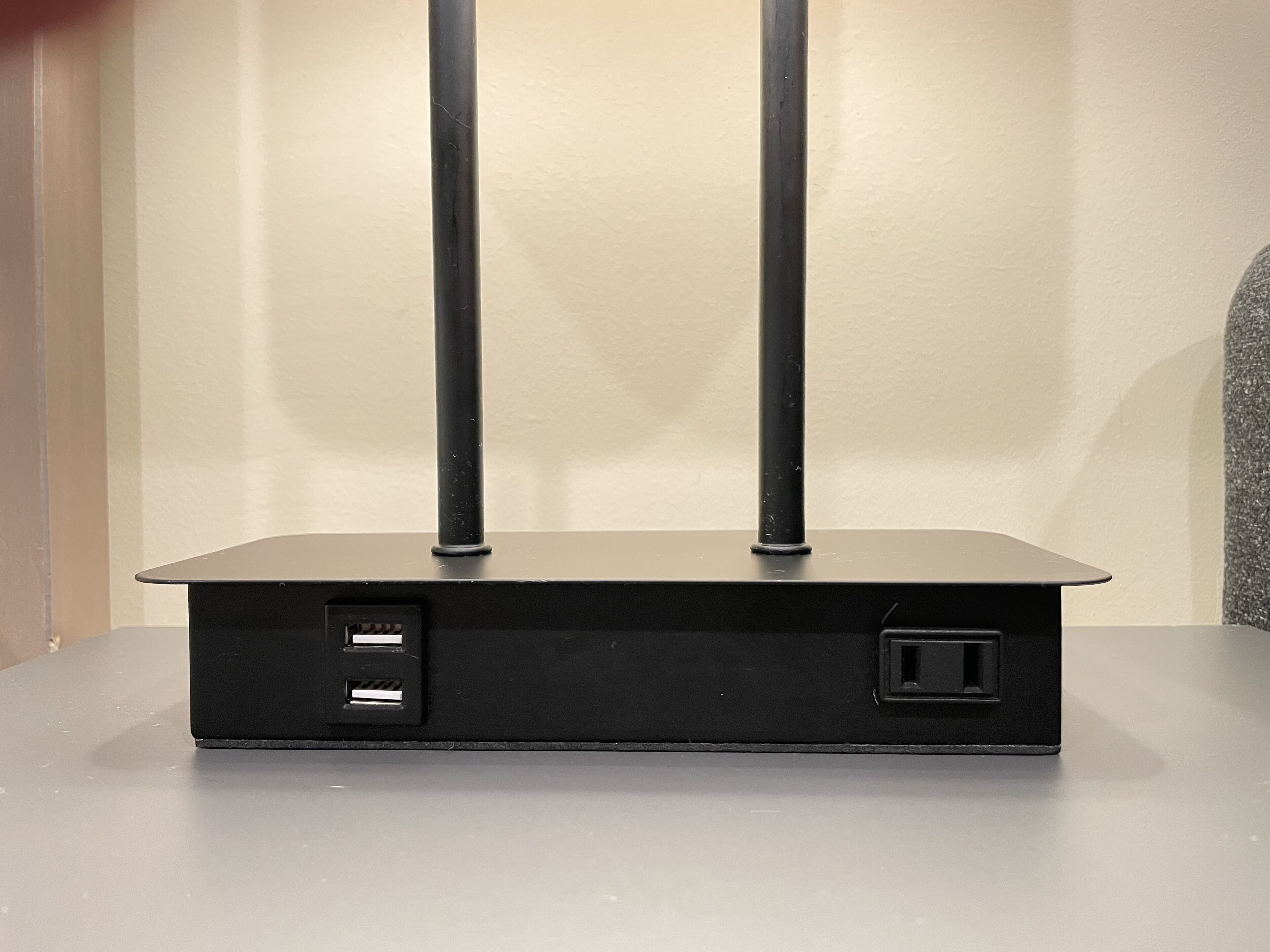 A black, rectangular electronic device with two antennas, two USB ports, and a power outlet on a flat surface.