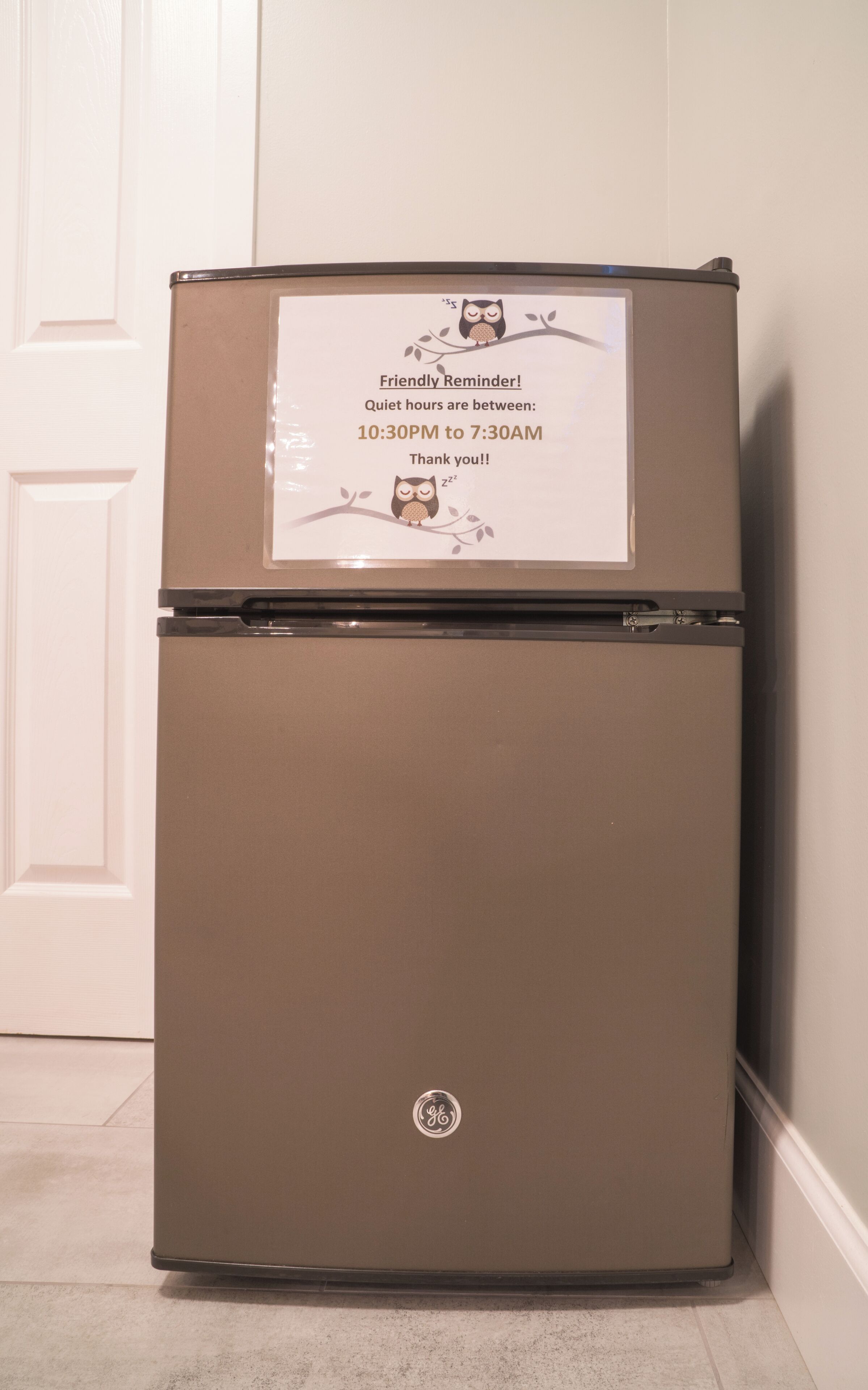 Un refrigerador GE marrón con un cartelito recordatorio en la parte superior.