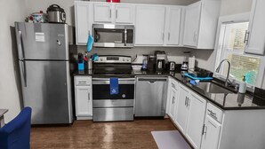 A compact kitchen with white cabinets, stainless steel appliances, and a wooden floor. - Luxurious beds, remodeled, very clean, quiet neighborhood, big backyard & tree!! (Denison)