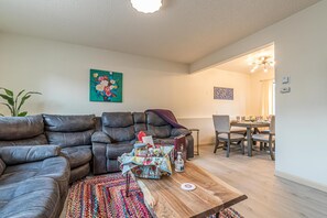 Ein Wohnzimmer mit Ledersofa, Couchtisch und Essbereich mit Tisch und Stühlen.
