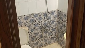 Ein Badezimmer mit Toilette, Dusche und Fliesen mit Blumenmuster.