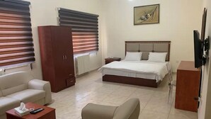 Ein Hotelzimmer mit einem Bett, einem Sofa, einem Holzschrank, einem kleinen Tisch und einem Fernseher.