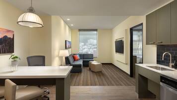 A modern kitchen with a dining area, a sofa, and a large window with a city view.