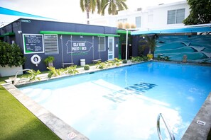 Una piscina con un mural de paisaje tropical, un cartel que dice "Isla Verde Puerto Rico" y un letrero que indica "No hay salvavidas de guardia". 