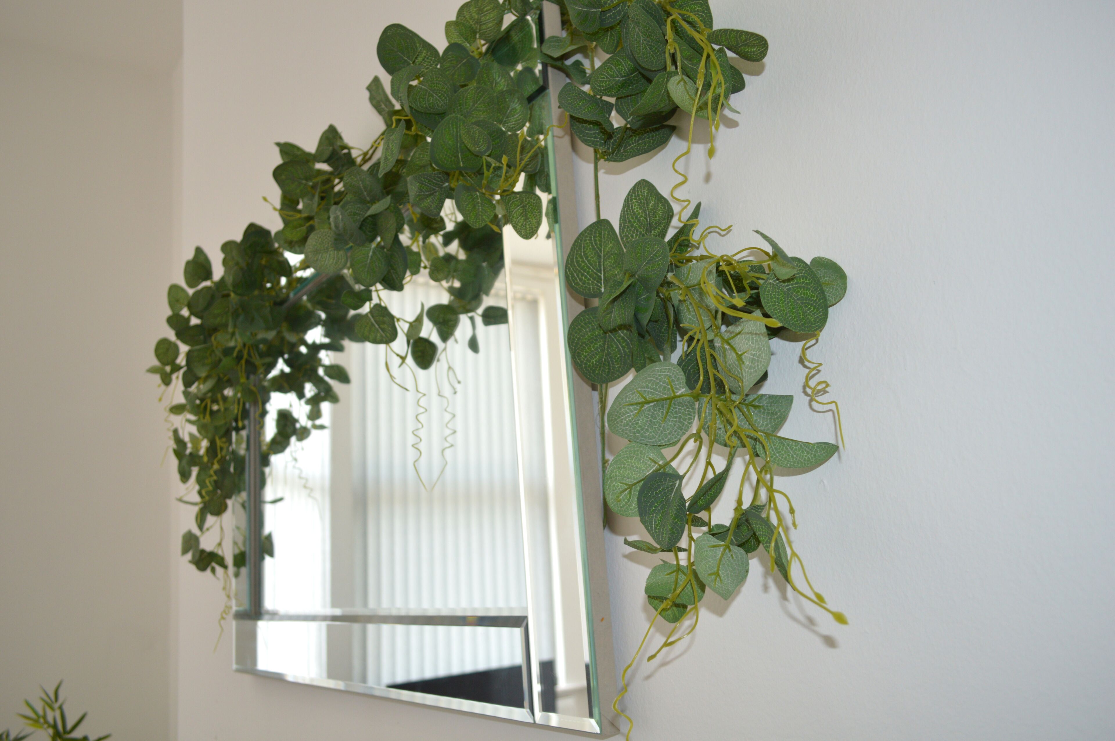 A mirror with a green leafy vine decoration.