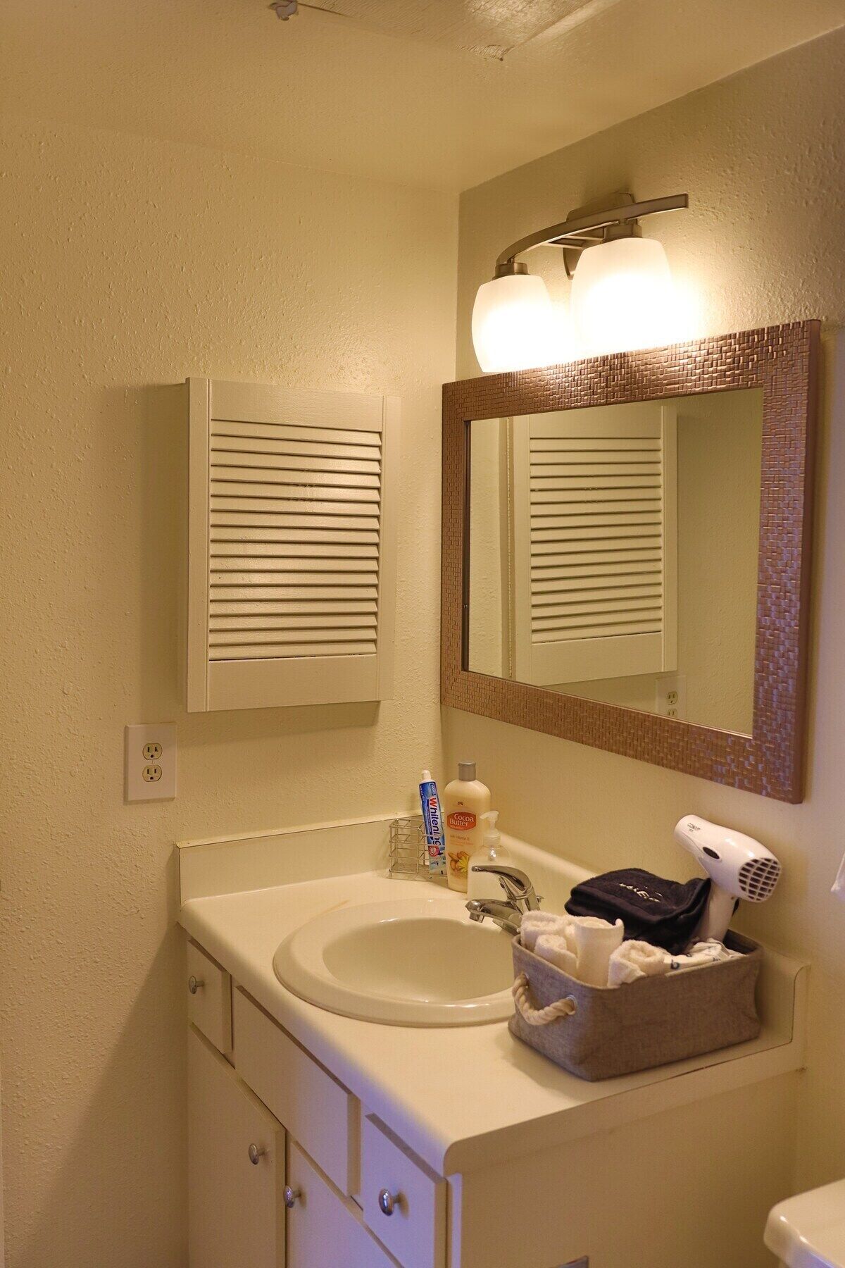 A bathroom with a sink, mirror, and toiletries.