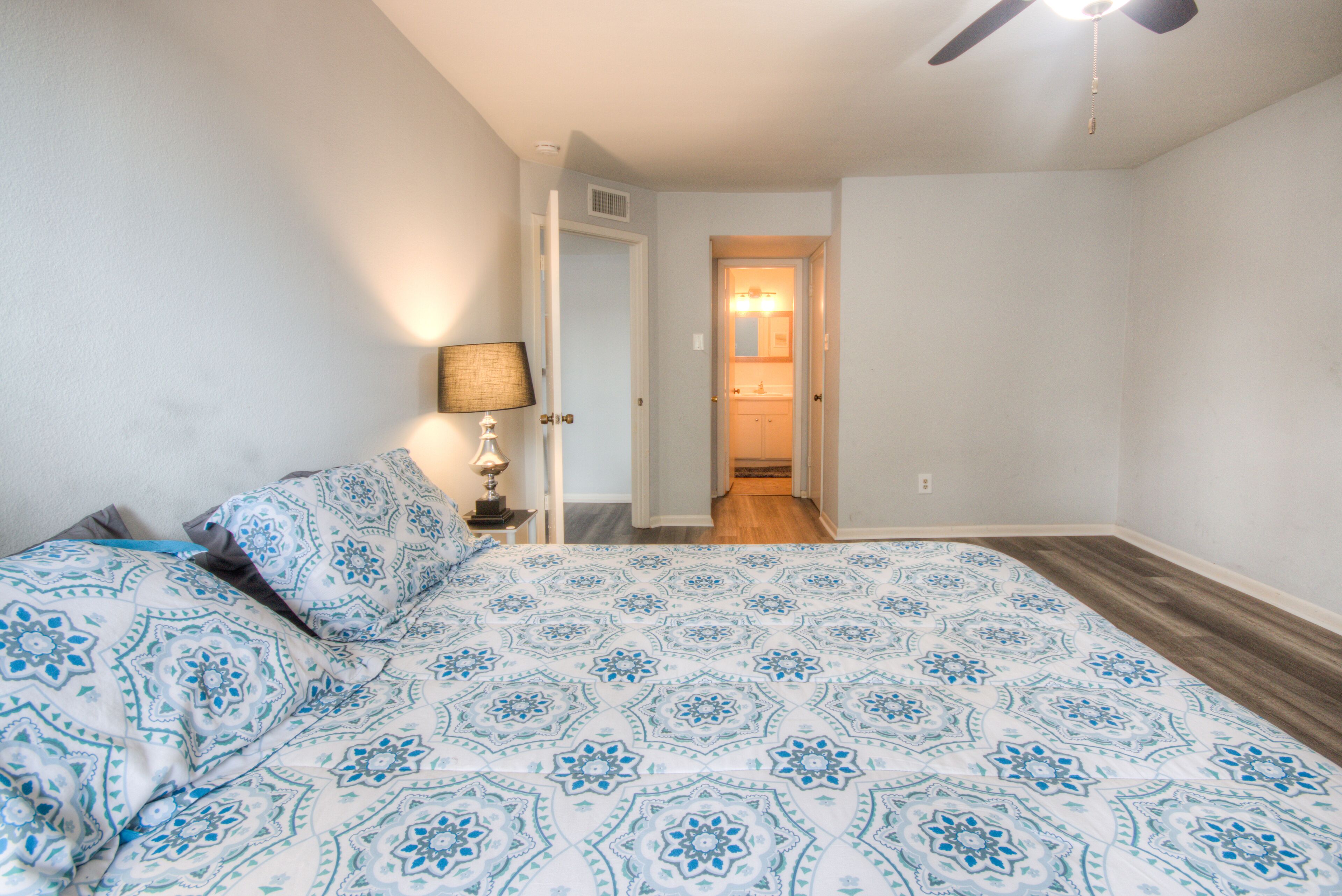 A bedroom with a bed, a nightstand, a lamp, and a ceiling fan.