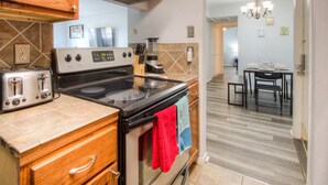 A kitchen with a stove, oven, and toaster. There is a dining area with a table and chairs.