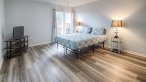 A bedroom with a bed, ceiling fan, and a TV on a wooden stand.