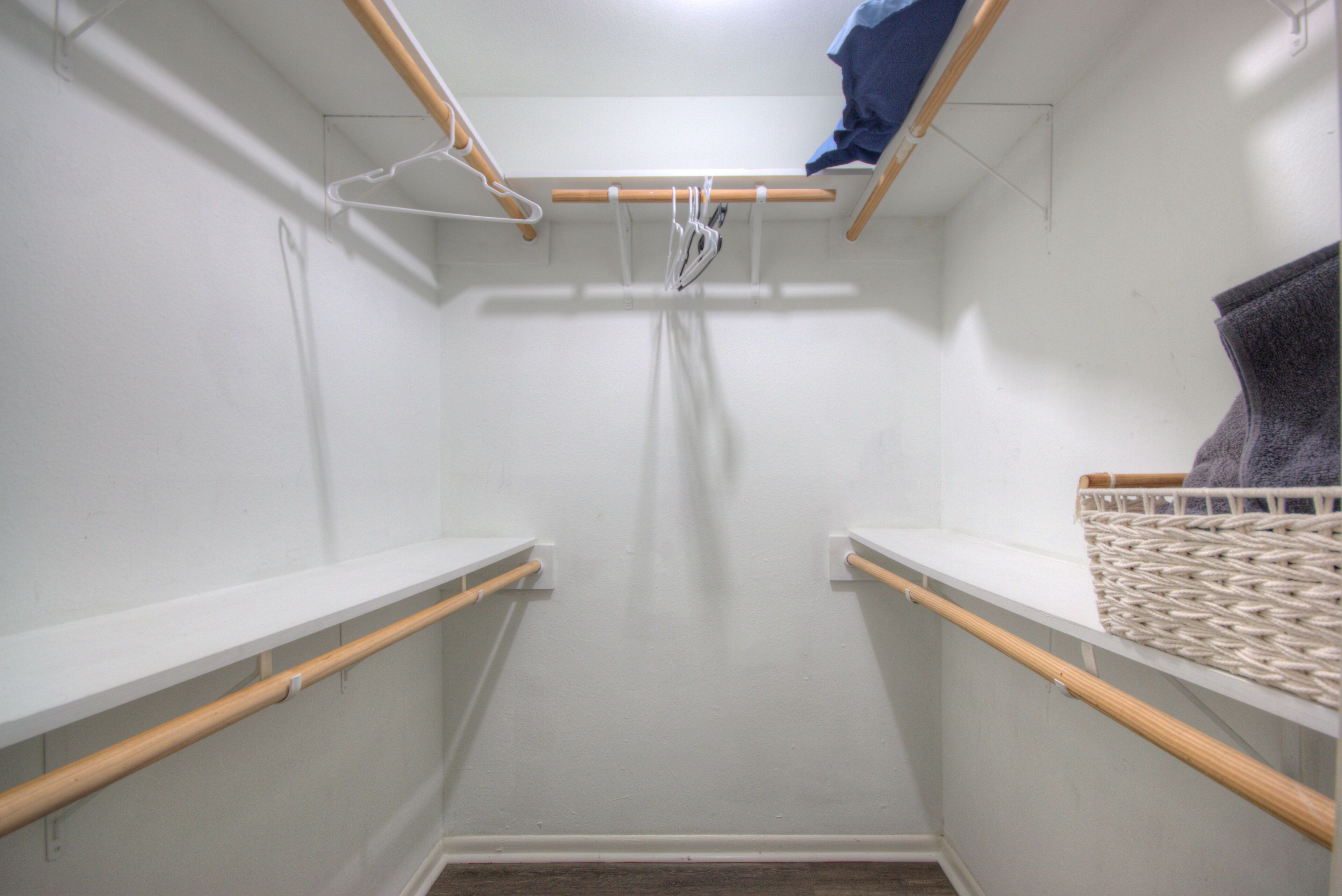 A small, enclosed laundry area with wooden shelves and a hanging rack.