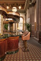 A luxurious lobby with a marble reception desk, a bar area with stools, and a patterned floor.