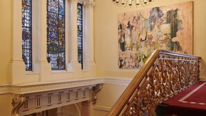 A grand staircase with ornate railings, a chandelier, and stained glass windows. - Gleneagles Townhouse (Edinburgh)